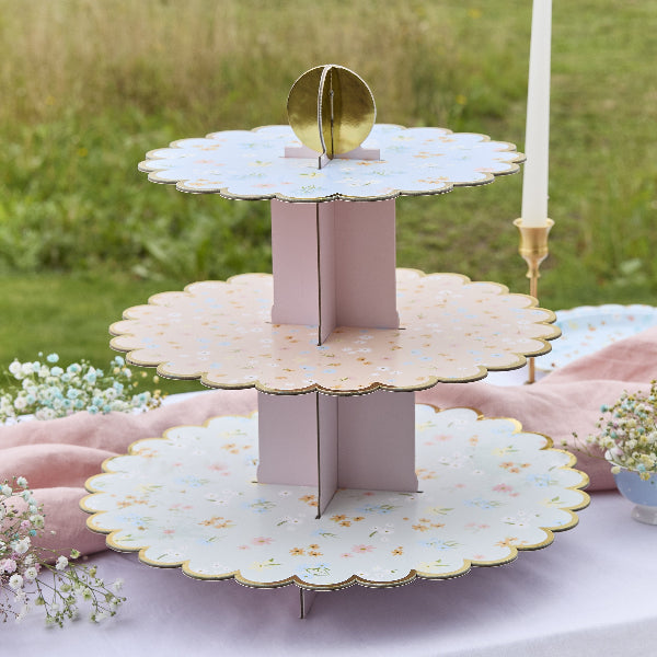 Three-tiered decorative stand with floral patterns on a table outdoors.